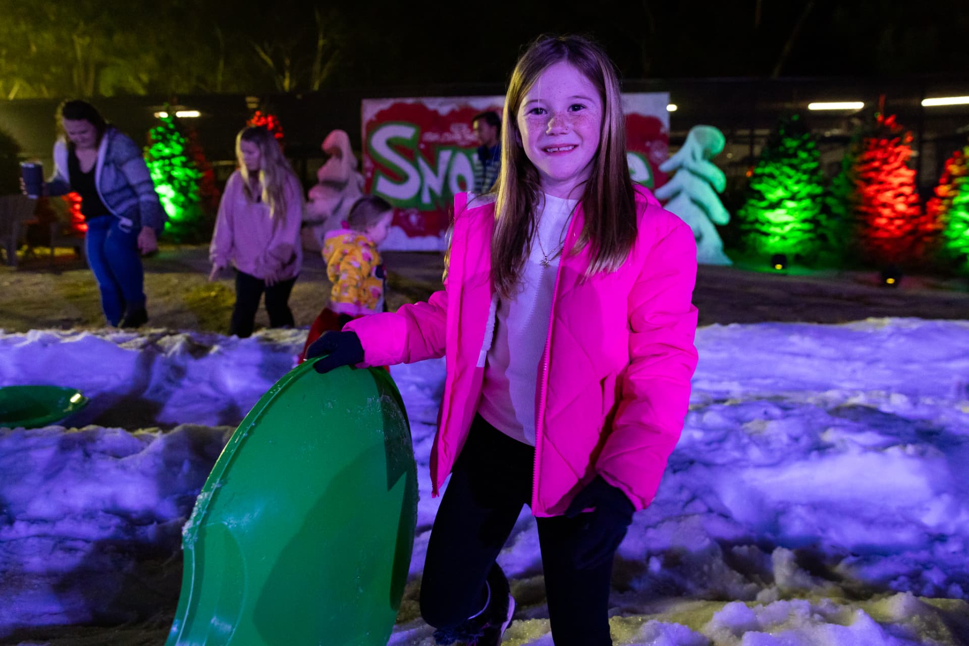 Girl with a green sled in the SnowSide snow play area
