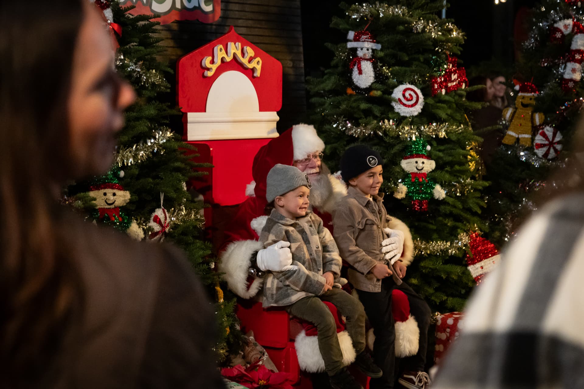 Two kids sitting with Santa by a decorated Christmas tree