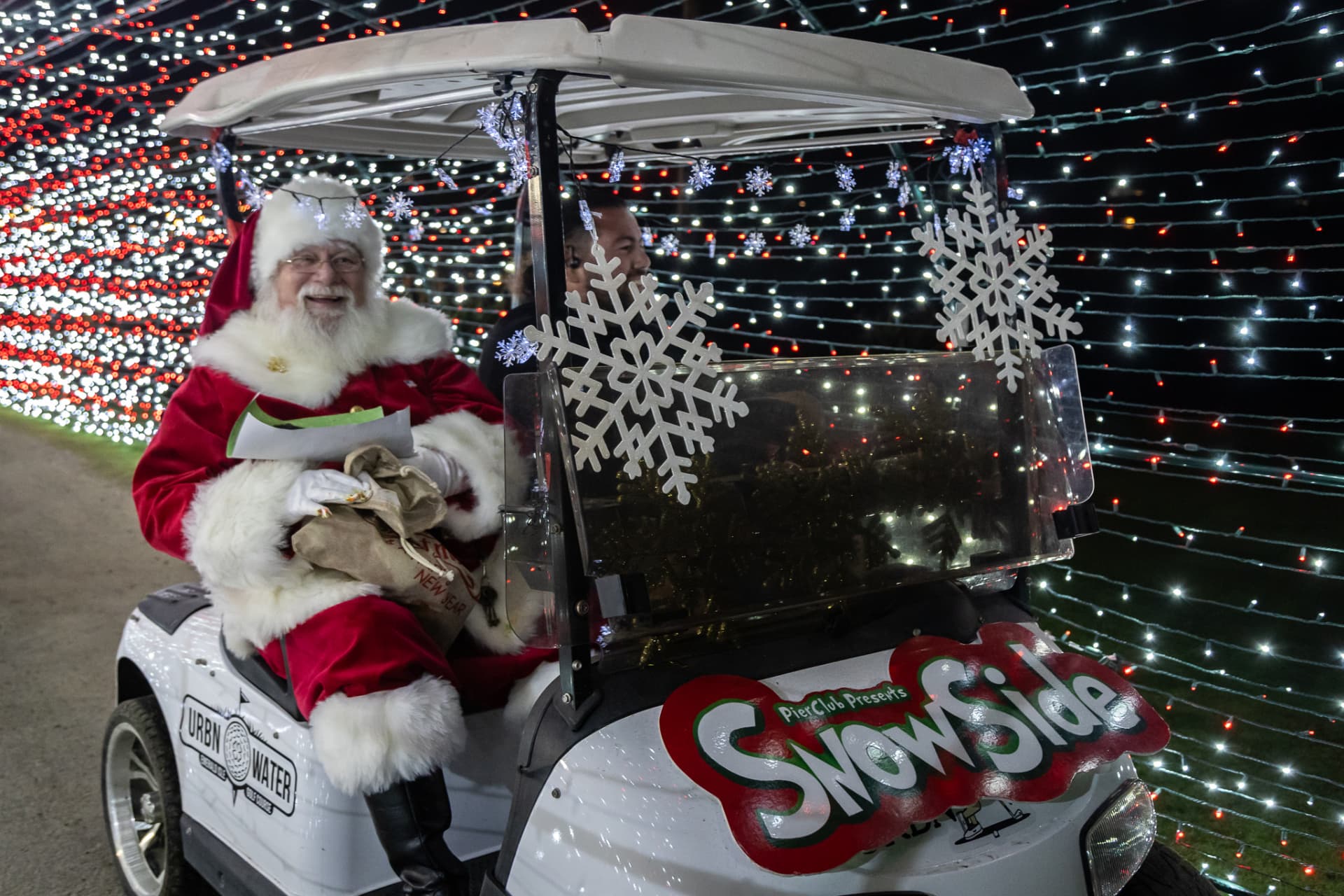 Santa waving from a light-covered cart at SnowSide